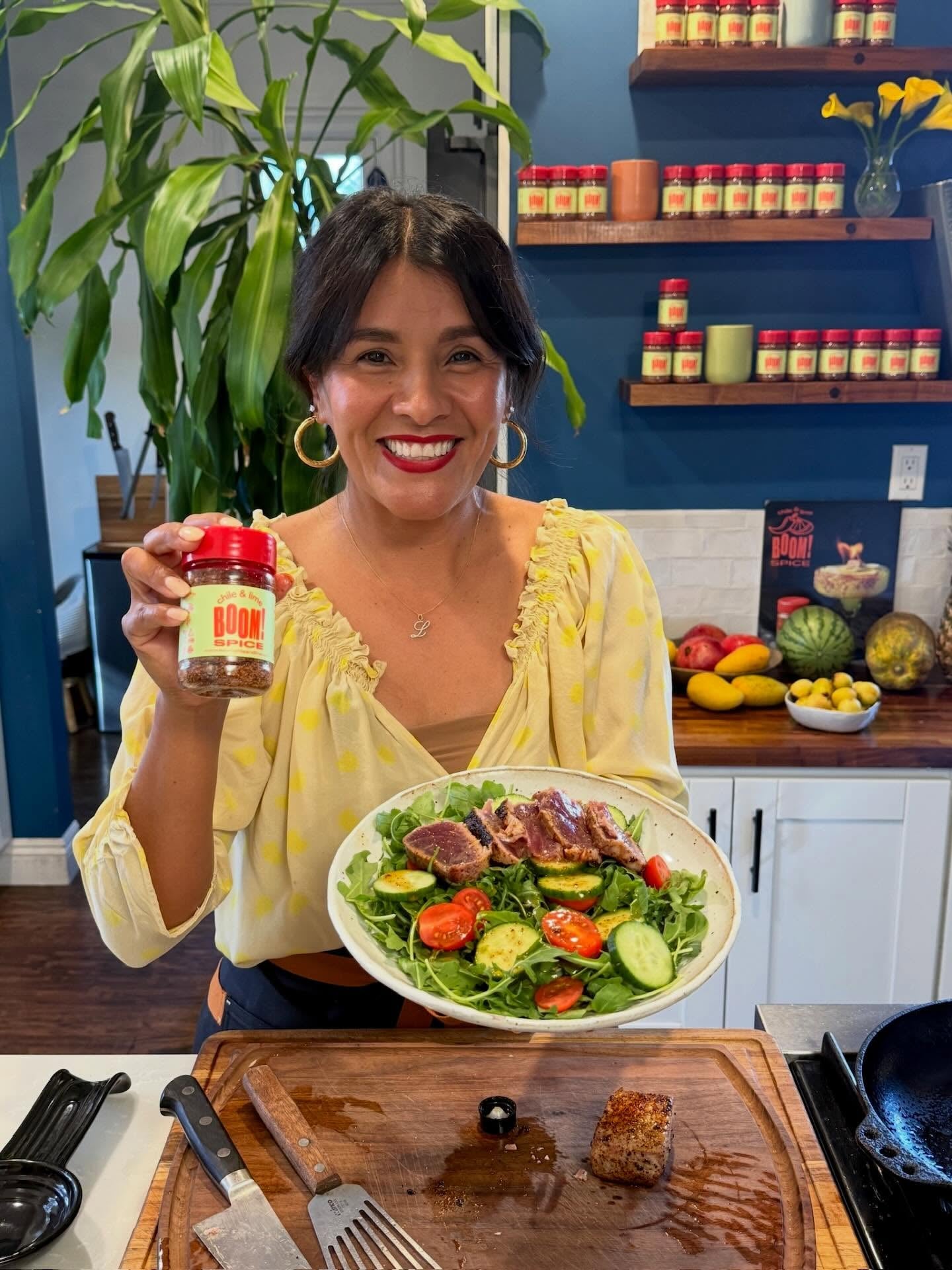 Woman holding a plate of salad and a jar of sauce in a kitchen.