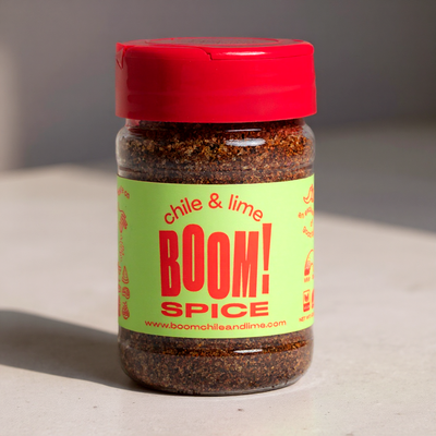 Jar of 'Chile & Lime BOOM! Spice' with a red lid on a neutral background