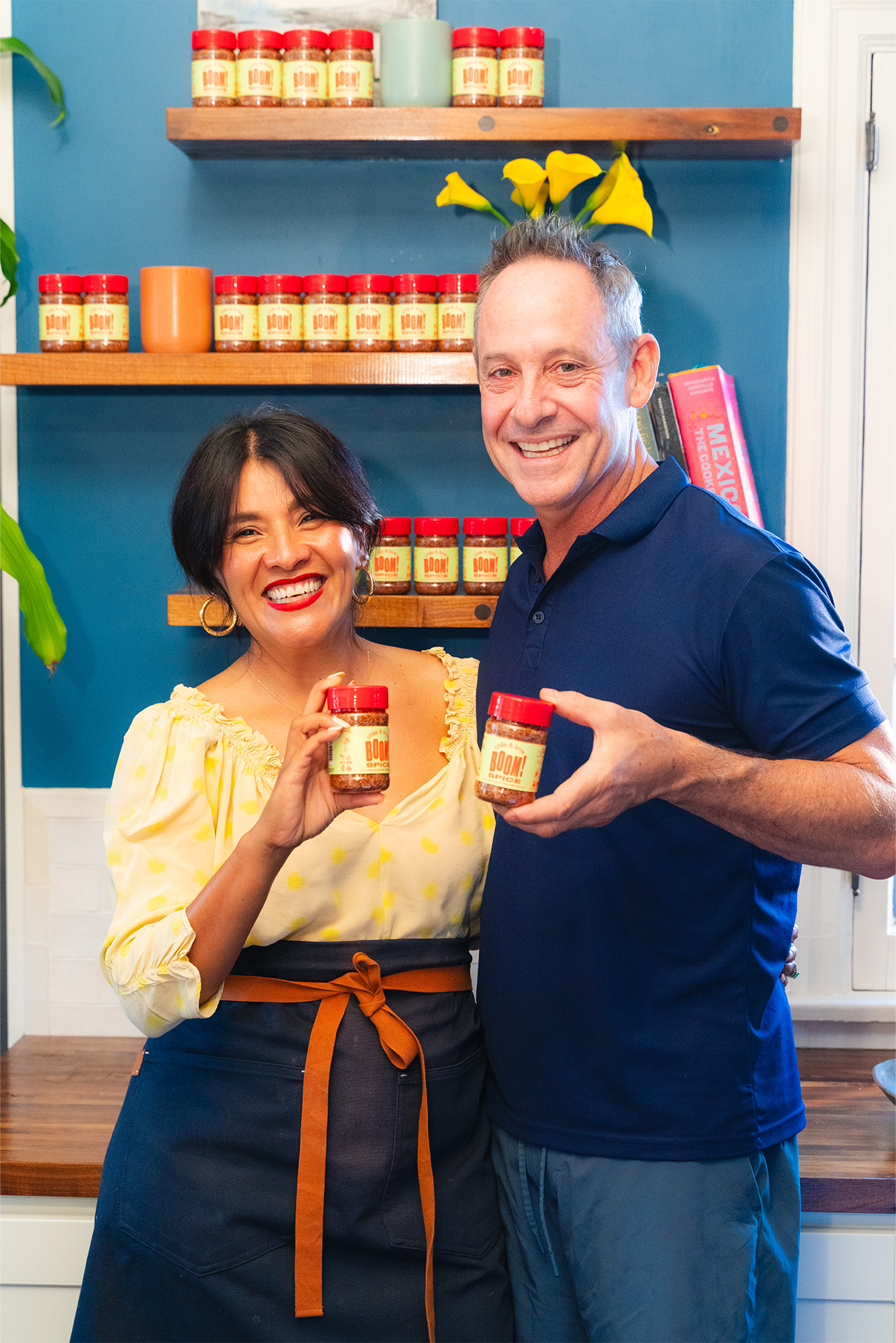 Two people holding jars of a product in front of shelves with more jars.